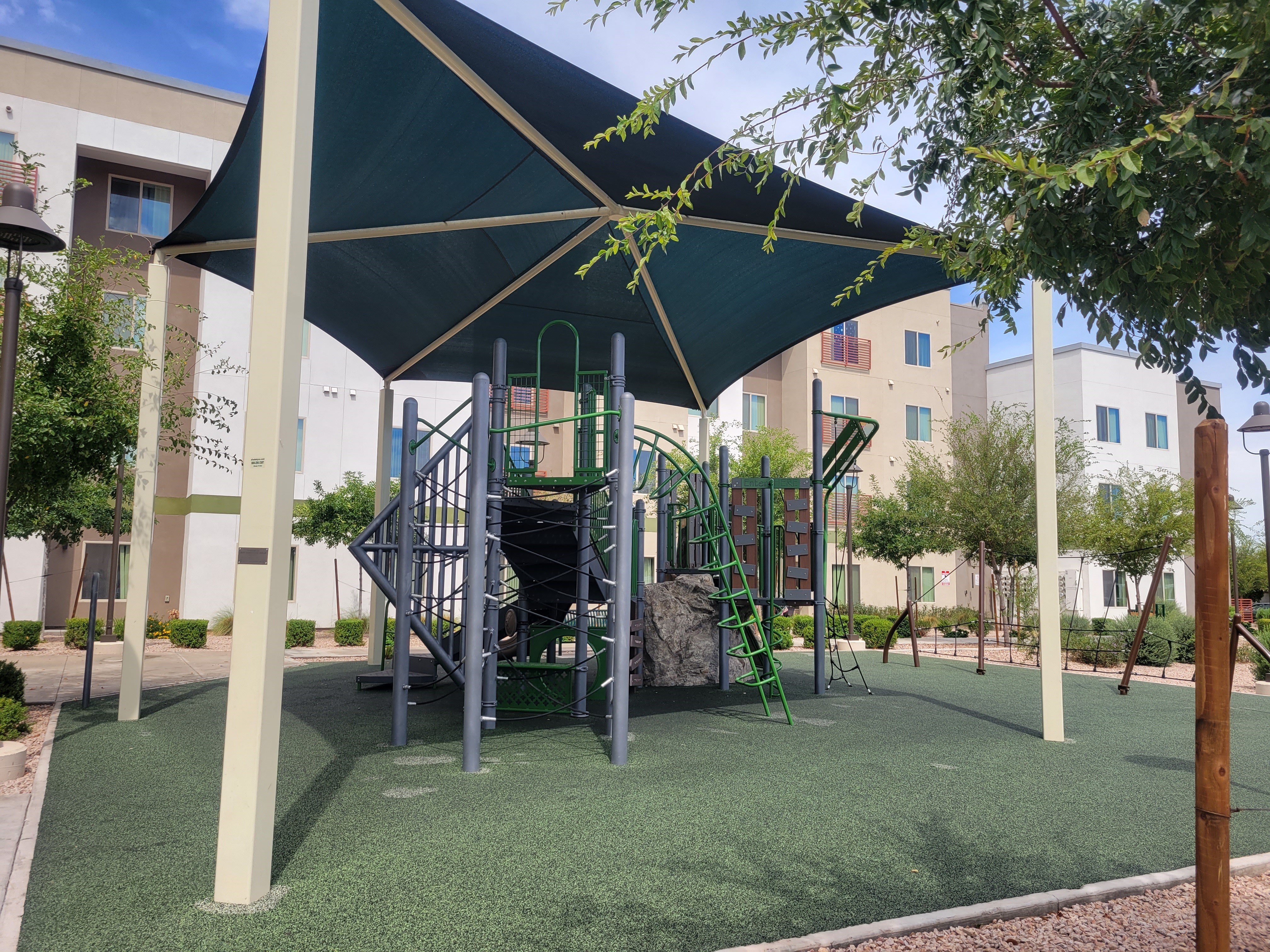 a playground with a slide and climbing equipment in an apartment complex